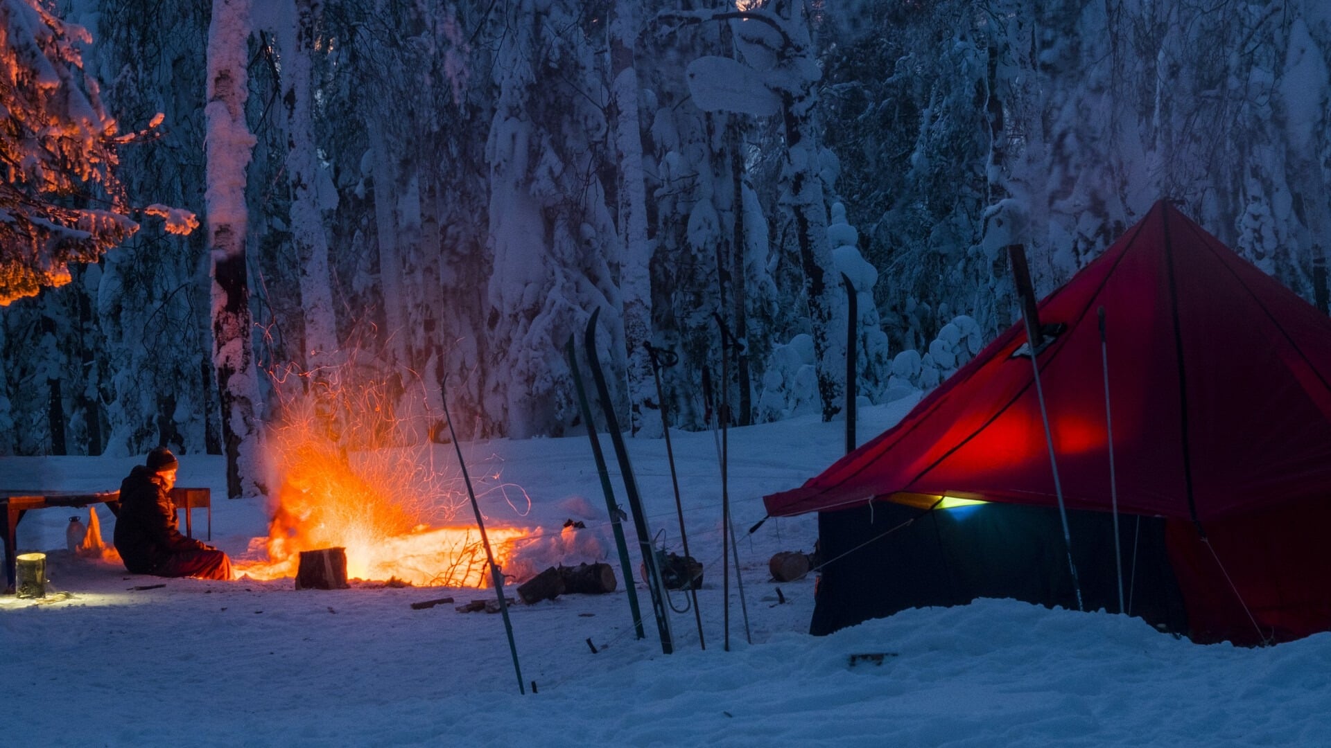 A cozy winter camping scene with a blazing campfire 